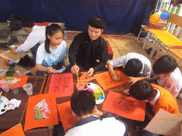 Nghệ nhân Đào Đình Trung đang dạy các em học sinh vẽ tranh đỏ