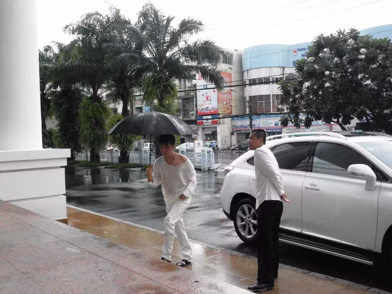 Mr Đàm cầm dù bước ra.