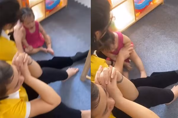 Clip ghi lại hình ảnh nữ giáo viên cơ sở mầm non tư thục Ngôi Sao Nhỏ ấn đầu bóp miệng bé gái 14 tháng tuổi, bên cạnh có một giáo viên khác nhưng không có sự can thiệp. (Ảnh cắt từ clip)