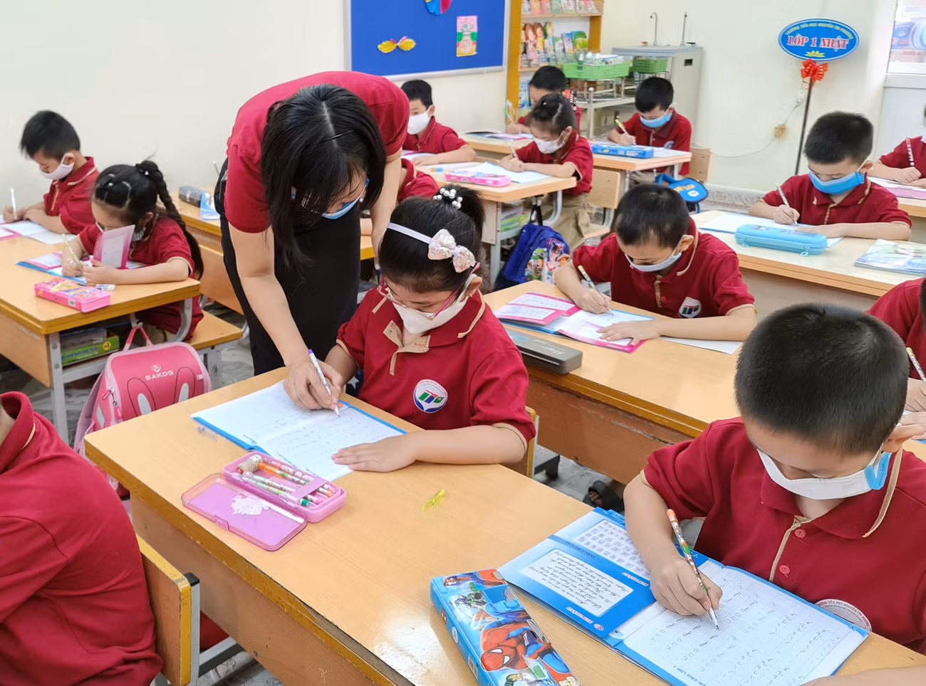 Học sinh Trường Tiểu học Nguyễn Tri Phương (quận Hồng Bàng) được giáo viên hướng dẫn làm quen với sách giáo khoa (Ảnh: Lã Tiến)