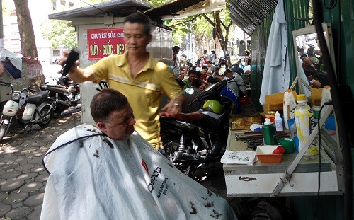 Ông Hans cắt tóc ở vỉa hè dưới sự tò mò quan sát của chúng tôi (Ảnh: tác giả cung cấp). Ông Hans cắt tóc ở vỉa hè dưới sự tò mò quan sát của chúng tôi (Ảnh: tác giả cung cấp).