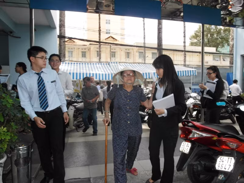 Hai nhân viên này đang giúp một cụ bà đến gửi tiền tiết kiệm bằng lương hưu trí.