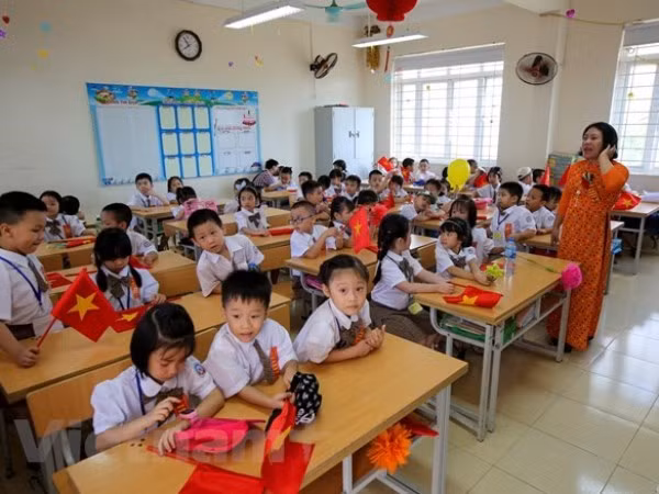 Bàn học được thiết kế cho hai học sinh nhưng vẫn phải xếp ba em vì quá tải. (Ảnh: Minh Sơn/Vietnam+)