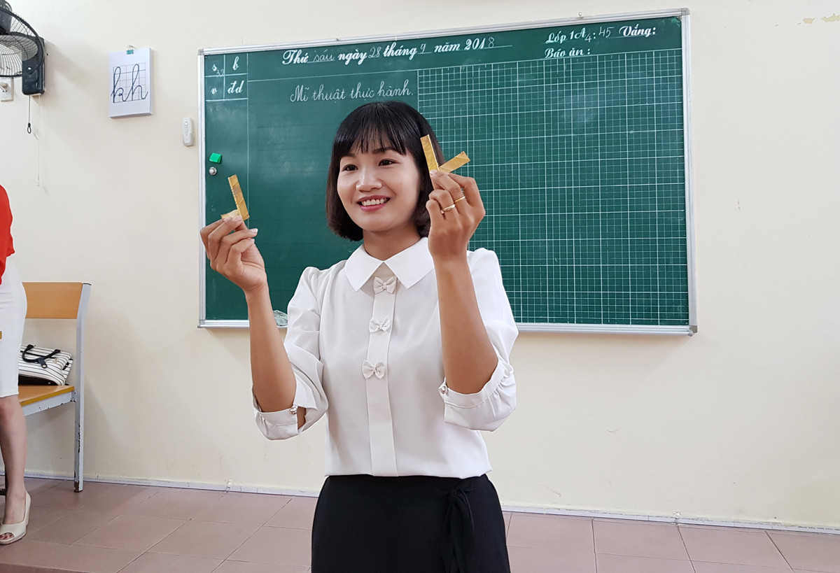 Cô giáo Hoàng Thị Hoa hướng dẫn học sinh lớp 1 tạo hình chú mèo từ lá cây khô (Ảnh: Lã Tiến) Cô giáo Hoàng Thị Hoa hướng dẫn học sinh lớp 1 tạo hình chú mèo từ lá cây khô (Ảnh: Lã Tiến)