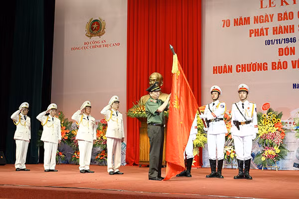 Thừa ủy quyền của Chủ tịch nước, Bộ trưởng Tô Lâm gắn Huân chương Bảo vệ Tổ quốc hạng nhất lên Cờ truyền thống của Báo Công an Nhân dân.