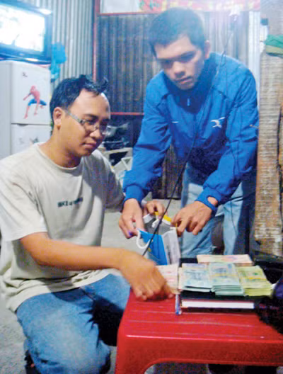 Trước khi đi chuộc xe, Đinh Đắc Lộc (ngồi) đã cùng với "hiệp sĩ" chuẩn bị tiền trong nhà trọ - Ảnh: do "hiệp sĩ" CLB phòng chống tội phạm P. Phú Hòa cung cấp