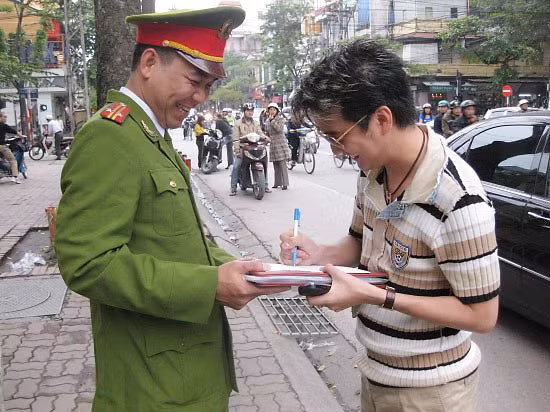 Mr Đàm ký tặng chiến sĩ công an. Từ xa, một đôi nam nữ tò mò đứng nhìn. Mr Đàm ký tặng chiến sĩ công an. Từ xa, một đôi nam nữ tò mò đứng nhìn.