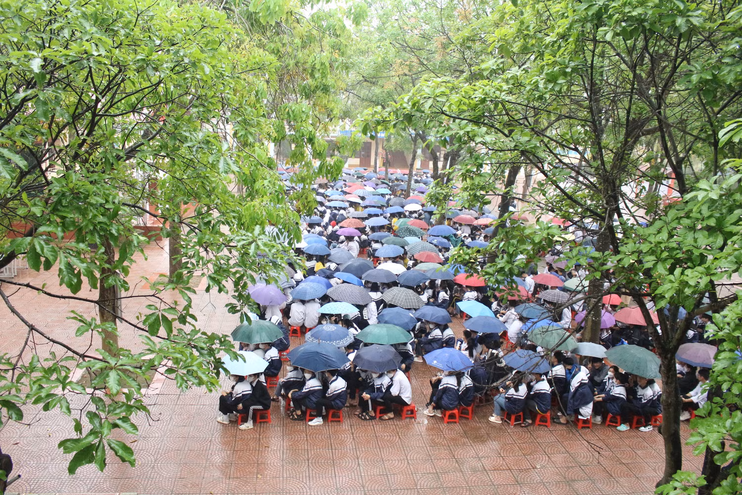 Gần 1.300 học sinh Trường Trung học phổ thông Hiệp Hòa số 4 "đội mưa" lắng nghe những chia sẻ của nhà văn Hoàng Anh Tú. Ảnh: Trung Dũng