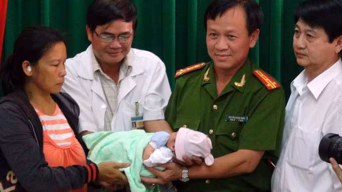 Bé Hoà được đại diện công an và Bệnh viện quận 7 trao lại cho chị Tâm - Ảnh: Đức Thanh