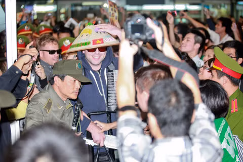 Mark đội nón lá do người hâm mộ tặng, tươi cười nói: "Hello Vietnam". Anh còn dùng điện thoại ghi lại hình ảnh người hâm mộ chào đón mình và các bạn. (Ảnh: VNE)
