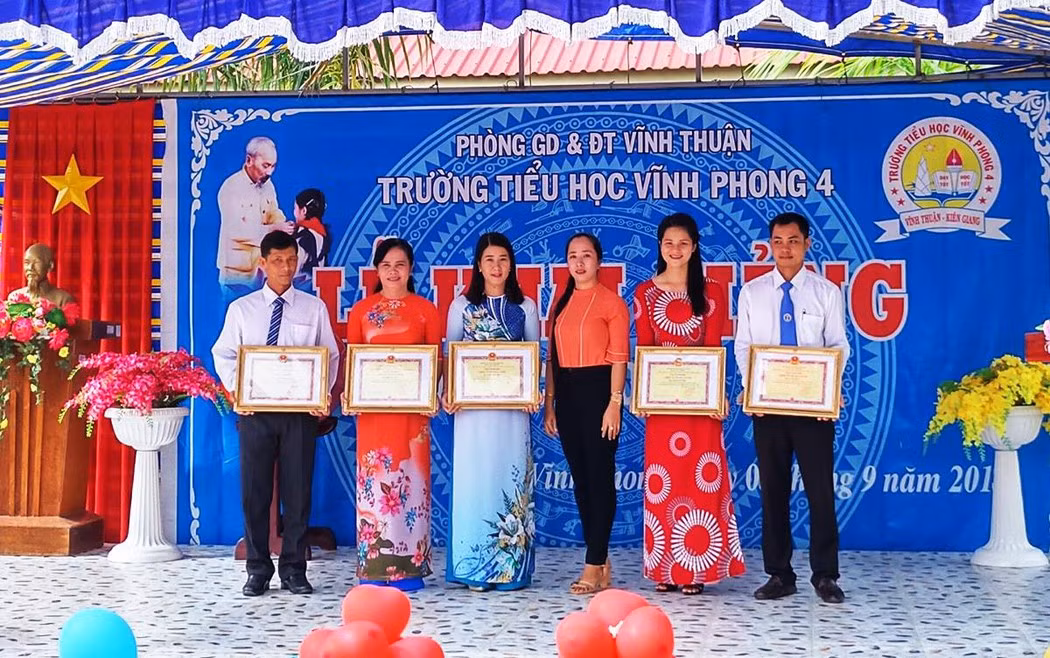 Cô Trịnh Ngọc Thuỳ Mai - Hiệu trưởng Trường Tiểu học Vĩnh Phong 4 (huyện Vĩnh Thuận, tỉnh Kiên Giang)(thứ 2 từ trái sang) đã “diễn kịch” nhận giấy chứng nhận tặng thưởng danh hiệu Chiến sĩ thi đua trên lễ đài dù không đạt thành tích này. (Ảnh: c1vinhphong4.vinhthuan.edu.vn).