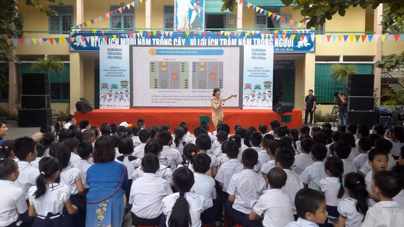 Các bạn học sinh tiểu học được các cô, chú Cảnh sát giao thông phổ biến kiến thức về an toàn giao thông. Ảnh: TT
