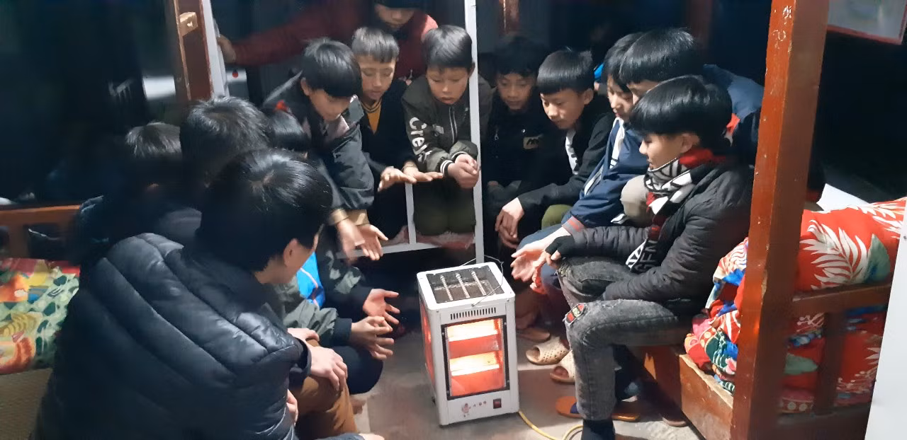 Các bạn học sinh nam ở trường Phổ thông dân tộc bán trú Sủng Là bên lò sưởi.