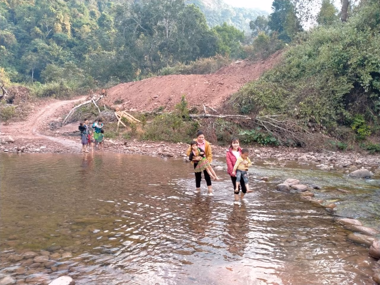 Buổi sáng cô Kim, cô Liệu đón học sinh qua suối lên lớp.