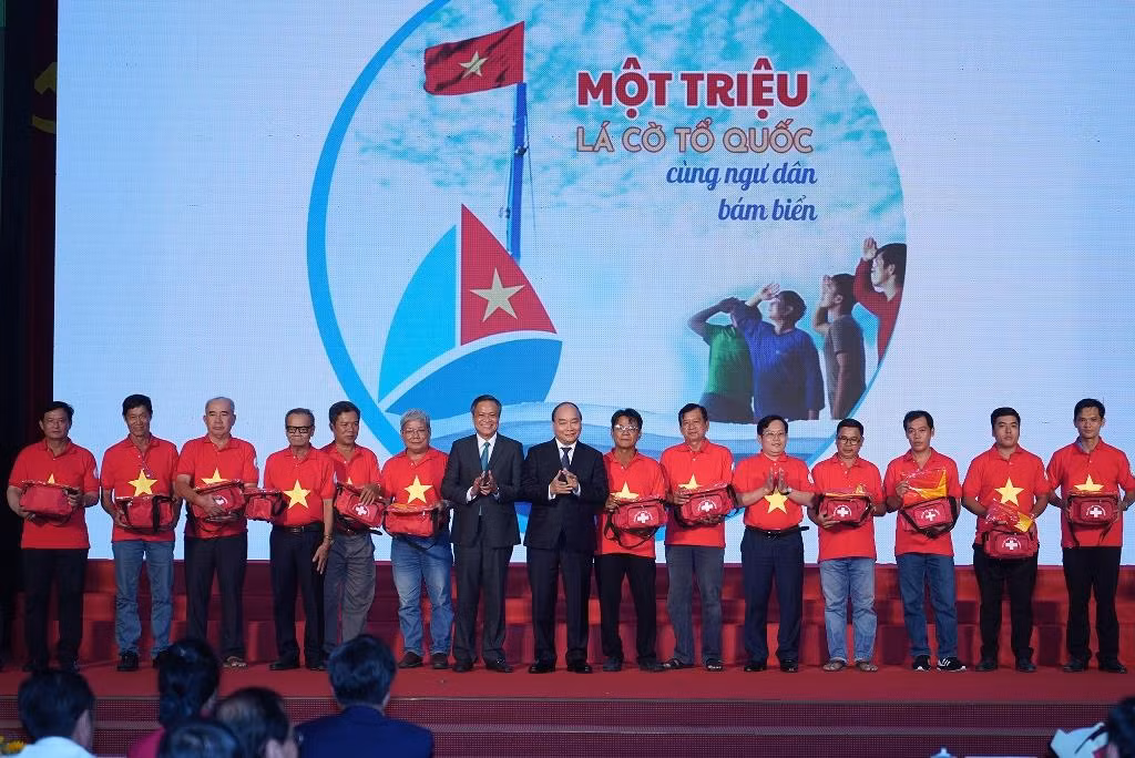 Thủ tướng trao cờ Tổ quốc và túi thiết bị y tế đi biển cho 12 ngư dân trong chương trình “Một triệu lá cờ Tổ quốc cùng ngư dân bám biển”. Ảnh: VGP