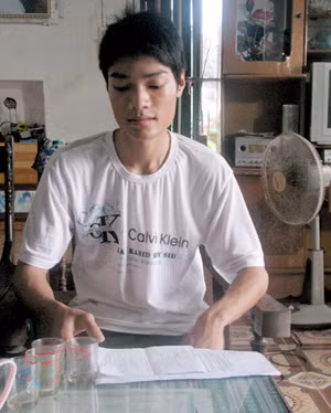 Vũ Viết Tiến bên giấy báo trúng tuyển đại học của trường Đại học Nông nghiệp và lệnh gọi công dân nhập ngũ