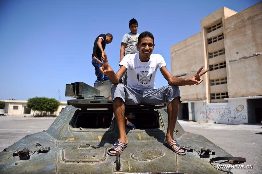 Một thanh niên Libya chụp ảnh bên một xe bọc thép bị bỏ lại ở Bab Al-azizia, Tripoli,