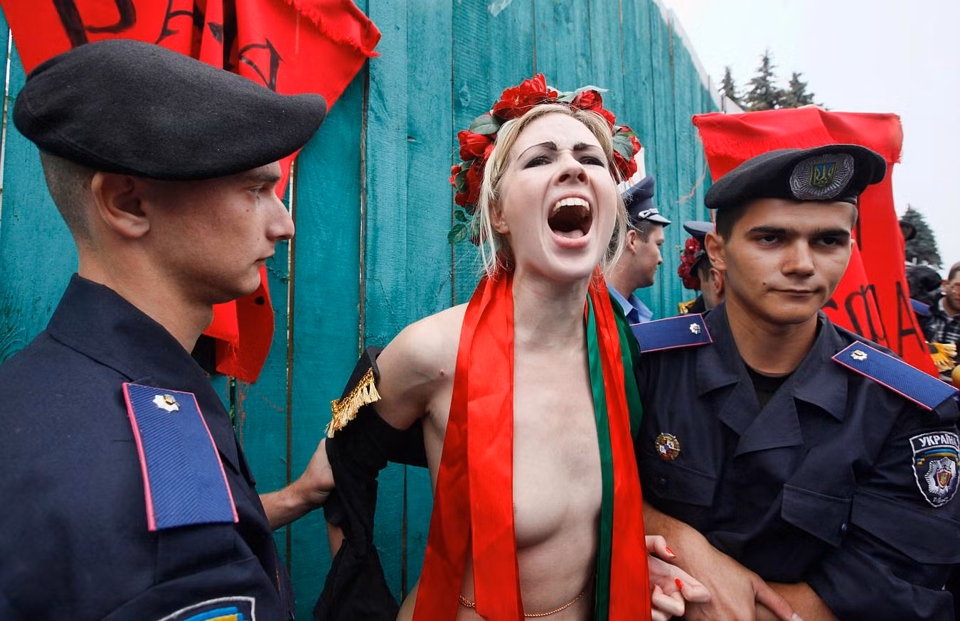 Cảnh sát bắt giữ một thành viên của FEMEN trước Quốc hội Ucraina phản đối cải cách quỹ lương hưu trong đó dự kiến sẽ nâng cao độ tuổi nghỉ hưu của phụ nữ