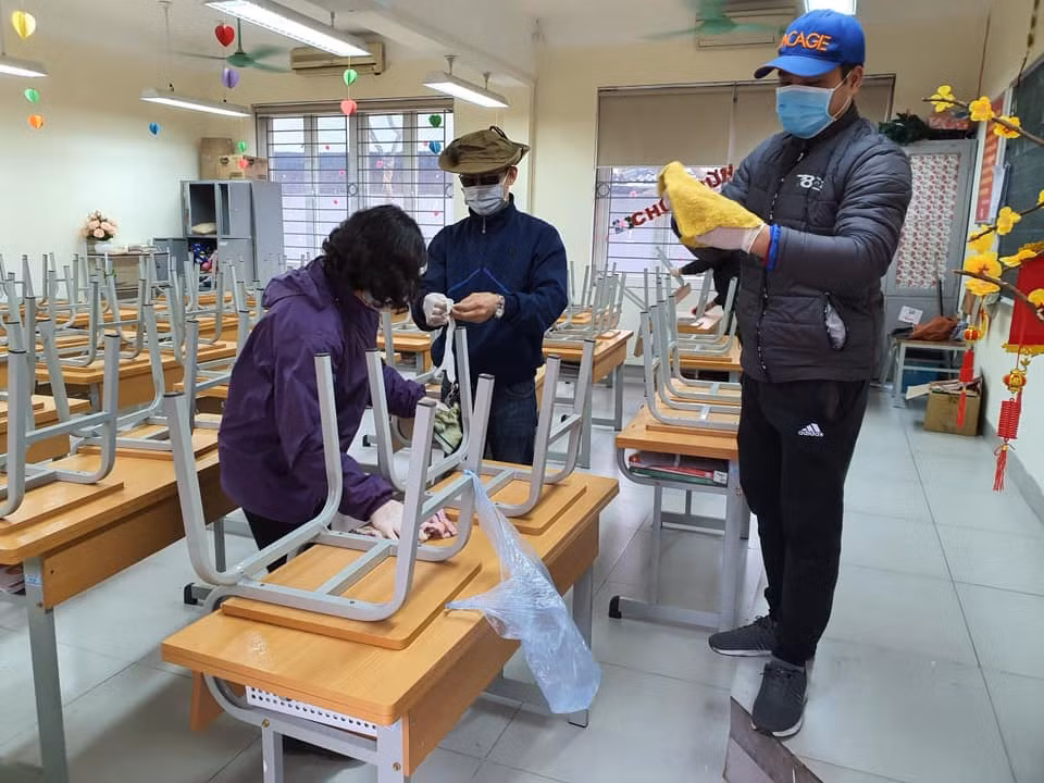 Giáo viên cùng phụ huynh Trường Tiểu học Phú Đô (Nam Từ Liêm) làm vệ sinh, khử trùng, sát khuẩn bàn ghế, phòng học. Ảnh: Tiểu học Phú Đô.