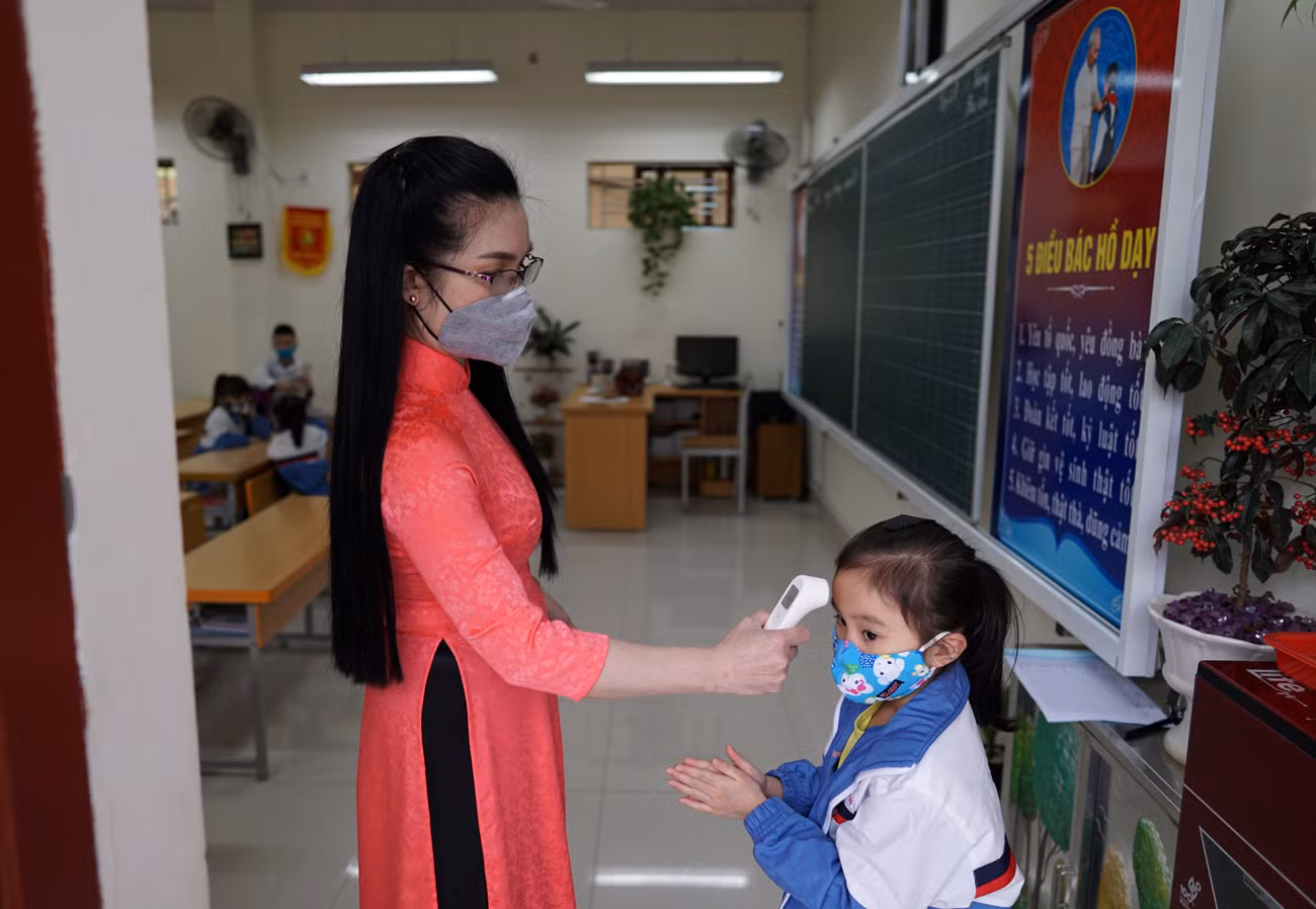 Giáo viên Trường Tiểu học Nguyễn Công Trứ (quận Lê Chân) đo nhiệt độ cơ thể cho học sinh trước khi vào lớp (Ảnh: LT)