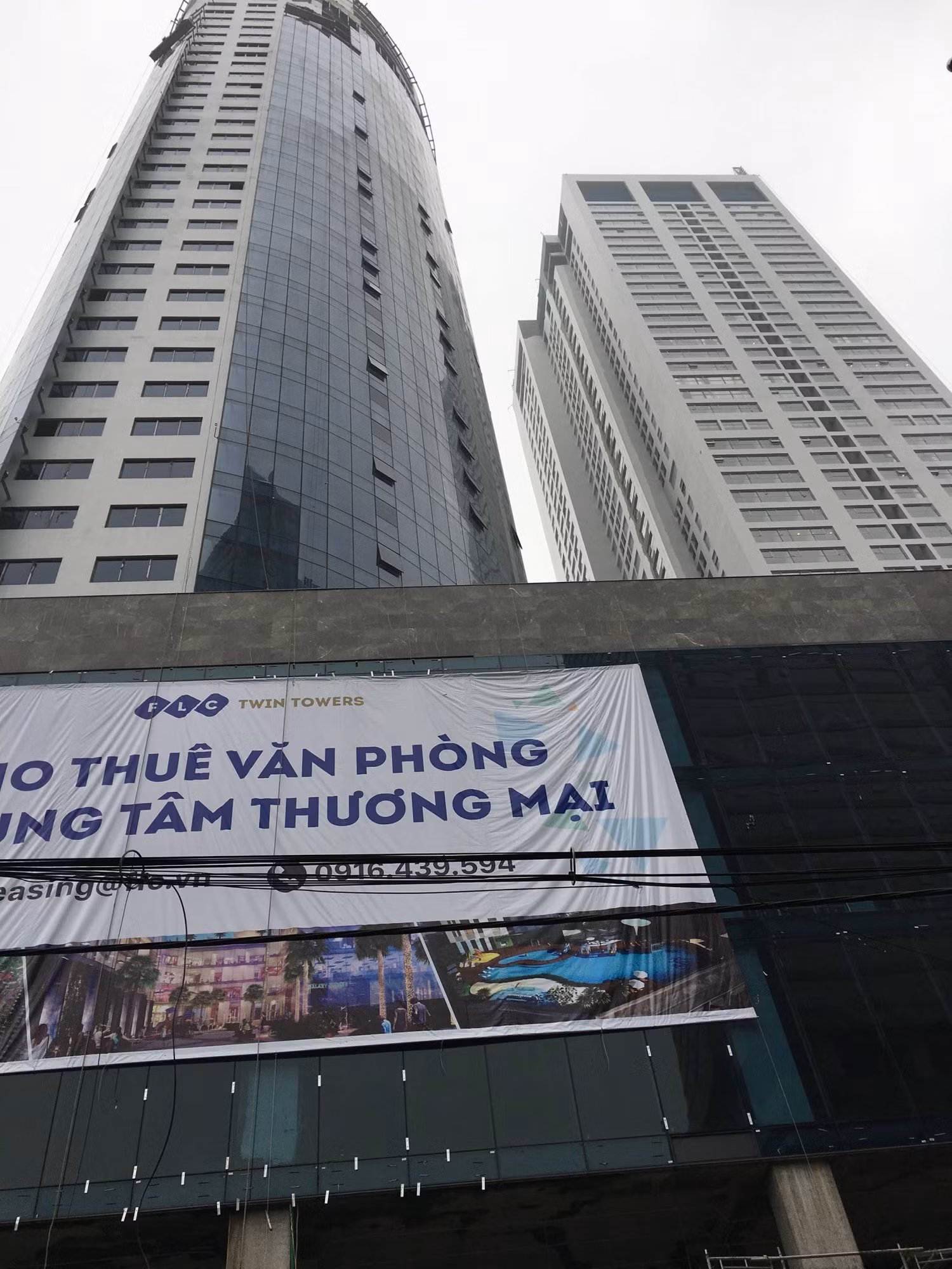 Tổ hợp nhà ở, văn phòng, trung tâm thương mại FLC Twin Towers số 265 Cầu Giấy đang hoàn thiện và đã có biển báo cho thuê văn phòng, nhưng nhiều hộ dân liền kề dự án bị hư hỏng chưa được đền bù thỏa đáng. Ảnh: V.P.