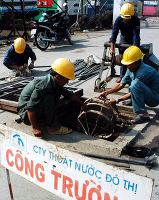 Công nhân Công ty Thoát nước đô thị thông cống chống ngập. Ảnh: THÁI BẰNG