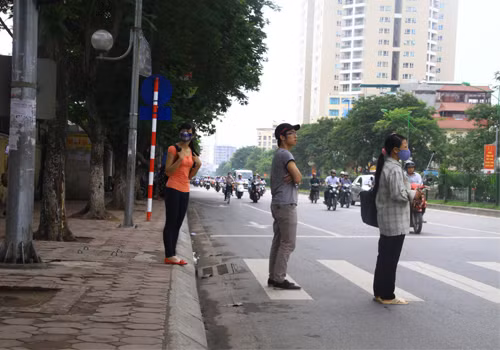 Người đi bộ đứng cả xuống lòng đường để chờ đèn tín hiệu.