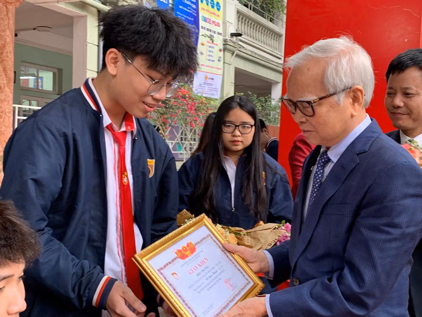 Tiến sĩ Nguyễn Văn Hòa - Chủ tịch Hội đồng quản trị Trường Trung học phổ thông Nguyễn Bỉnh Khiêm trao giấy khen cho em Đỗ Ngọc Thành dũng cảm tham gia bắt cướp. Ảnh: Tùng Dương.