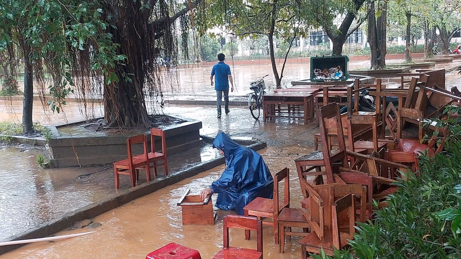 Thầy cô giáo phải mang bàn ghế học sinh ra vệ sinh, chùi rửa trong mưa. Ảnh: AN Thầy cô giáo phải mang bàn ghế học sinh ra vệ sinh, chùi rửa trong mưa. Ảnh: AN