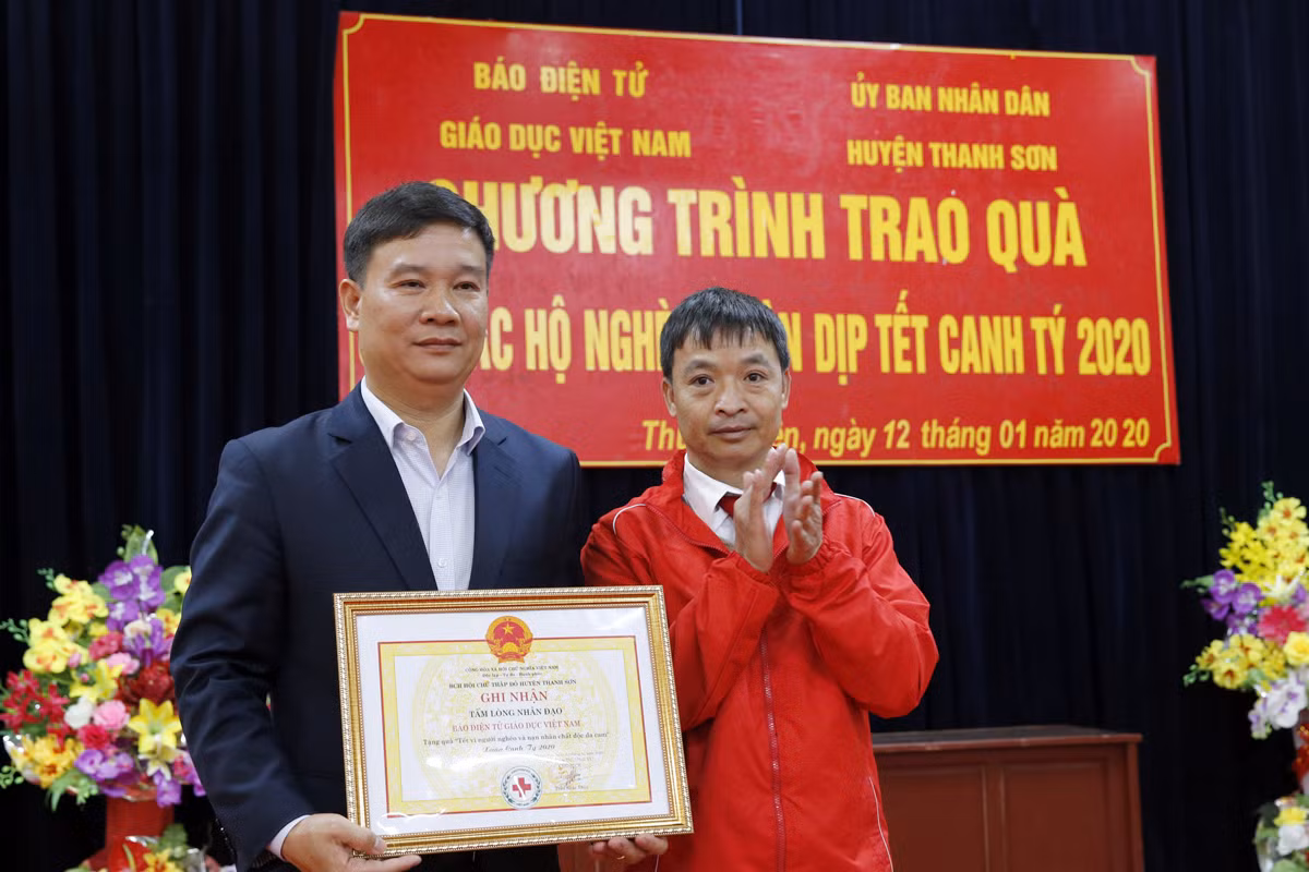 Nhà báo Nguyễn Tiến Bình - Tổng biên tập Báo điện tử Giáo dục Việt Nam (người bên trái ) đang nhận bảng nghi nhận của Hội chữ thập đỏ huyện Thanh Sơn về công tác tặng quà Tết cho người nghèo của huyện. Ảnh: Tùng Dương.