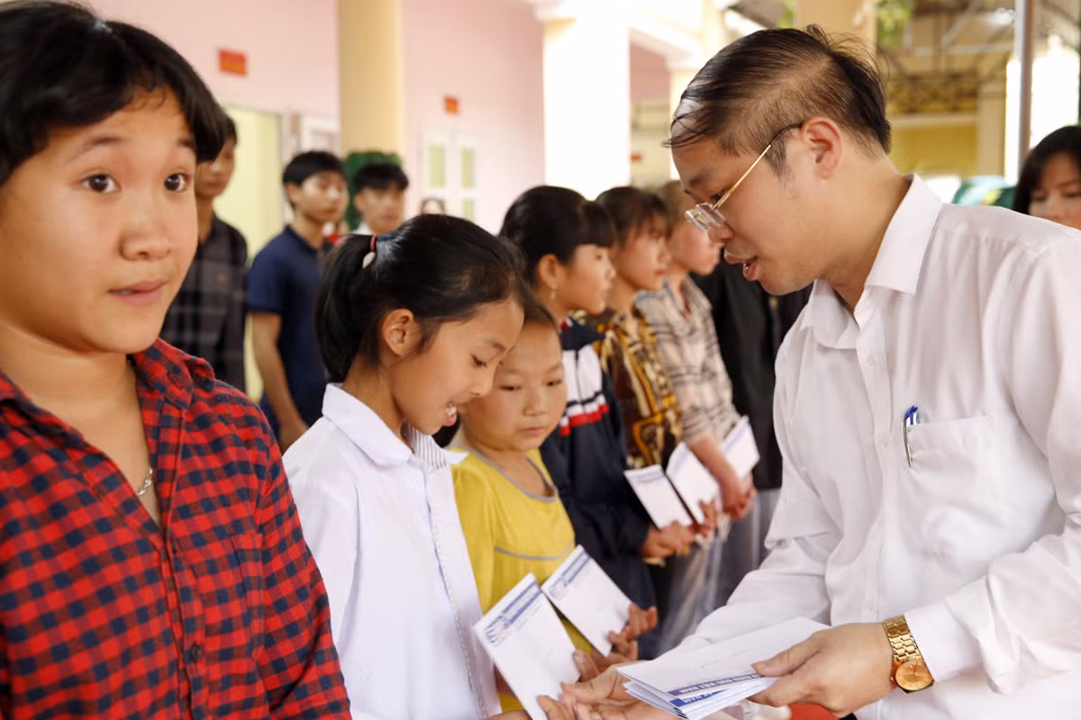 Ông Nguyễn Ánh Hoàng - Trưởng phòng Giáo dục và Đào tạo thị xã Phú Thọ, đang trao quà cho các em học sinh có hoàn cảnh khó khăn. Ảnh: Tùng Dương.