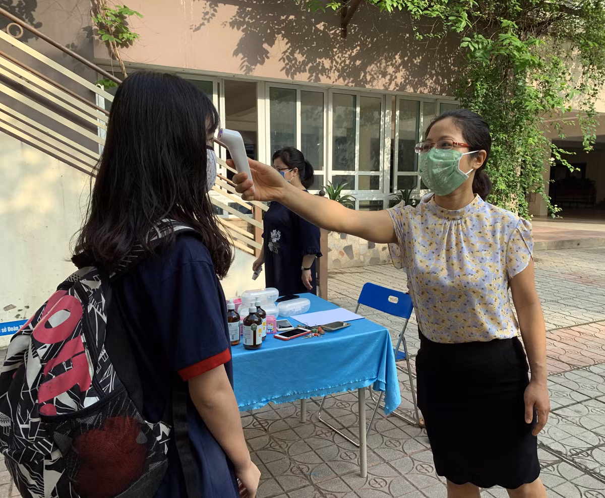 Trường Trung học cơ sở Đoàn Thị Điểm phân luồng khoảng cách, đo thân nhiệt từ cổng trước khi học sinh vào trường. Ảnh: Tùng Dương. Trường Trung học cơ sở Đoàn Thị Điểm phân luồng khoảng cách, đo thân nhiệt từ cổng trước khi học sinh vào trường. Ảnh: Tùng Dương.