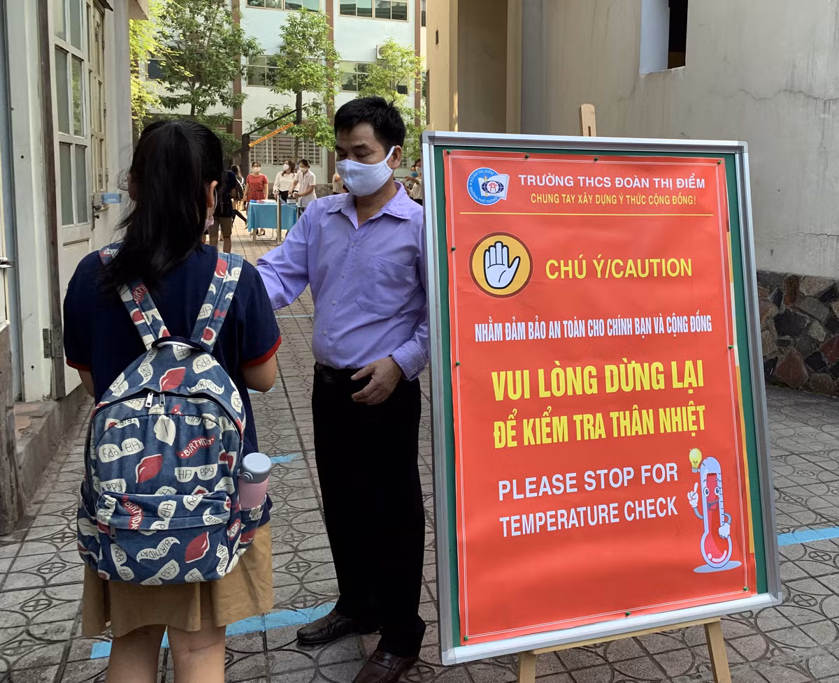 Trường luôn bố trí cán bộ tại các cổng trường để nhắc nhở học sinh về các biện pháp phòng dịch. Ảnh: Tùng Dương. Trường luôn bố trí cán bộ tại các cổng trường để nhắc nhở học sinh về các biện pháp phòng dịch. Ảnh: Tùng Dương.