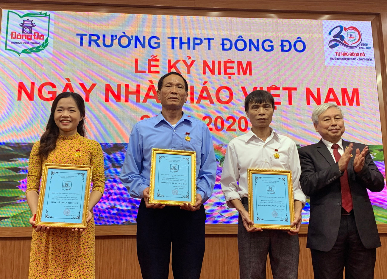 Tiến sĩ Võ Thế Quân (bên phải ảnh) - Hiệu trưởng Trường Trung học phổ thông Đông Đô đang trao Kỷ niêm chương vì sự nghiệp phát triển Đông Đô cho các giáo viên nhà trường. Ảnh: Tùng Dương.