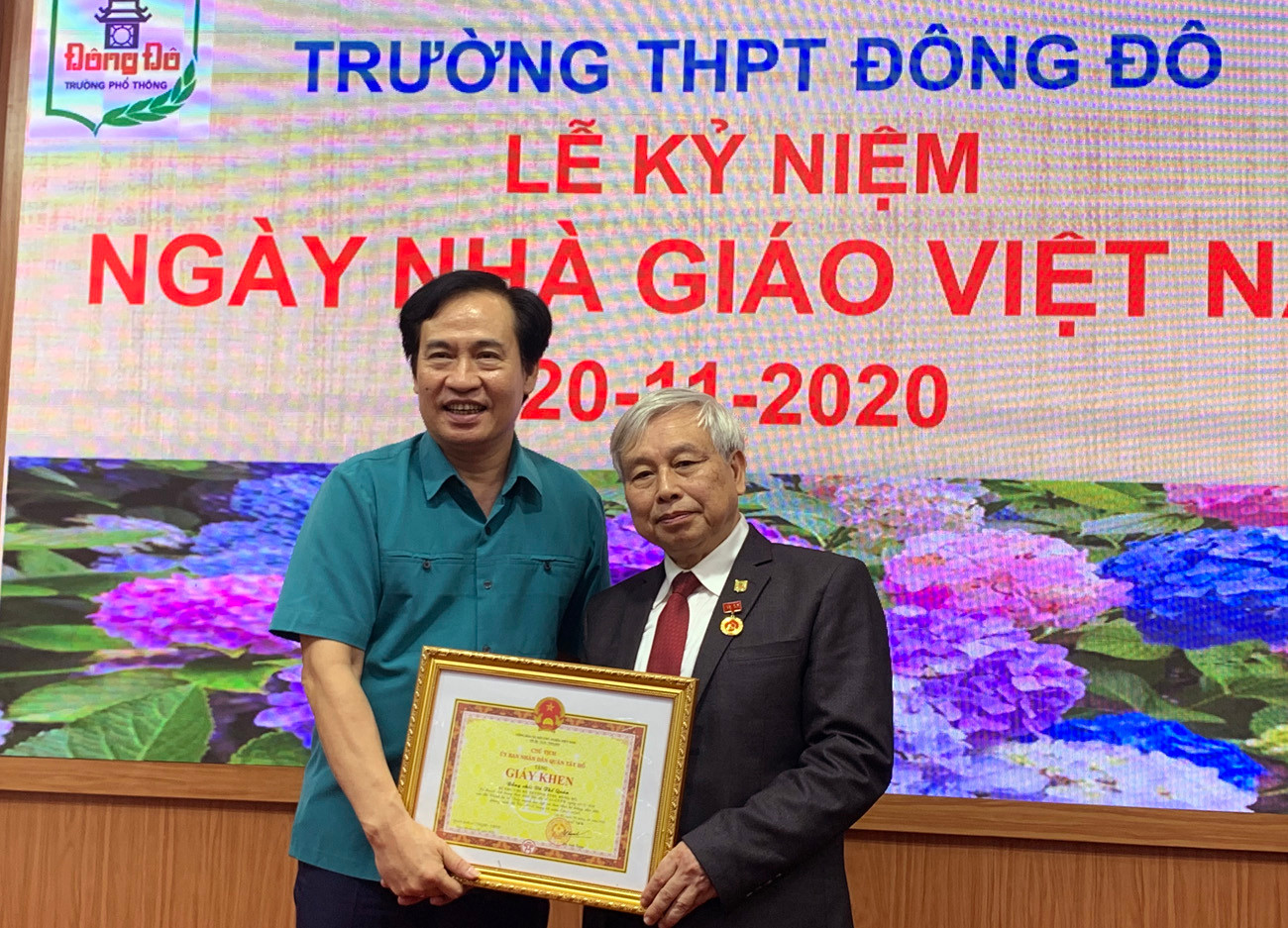 Ông Nguyễn Anh Tuấn (bên trái ảnh) Phó Bí thư thường trực quận Ủy Tây Hồ đang trao giấy khen và huy hiệu 40 năm tuổi Đảng cho Tiến sĩ Võ Thế Quân - Hiệu trưởng Trường Trung học phổ thông Đông Đô. Ảnh: Tùng Dương.
