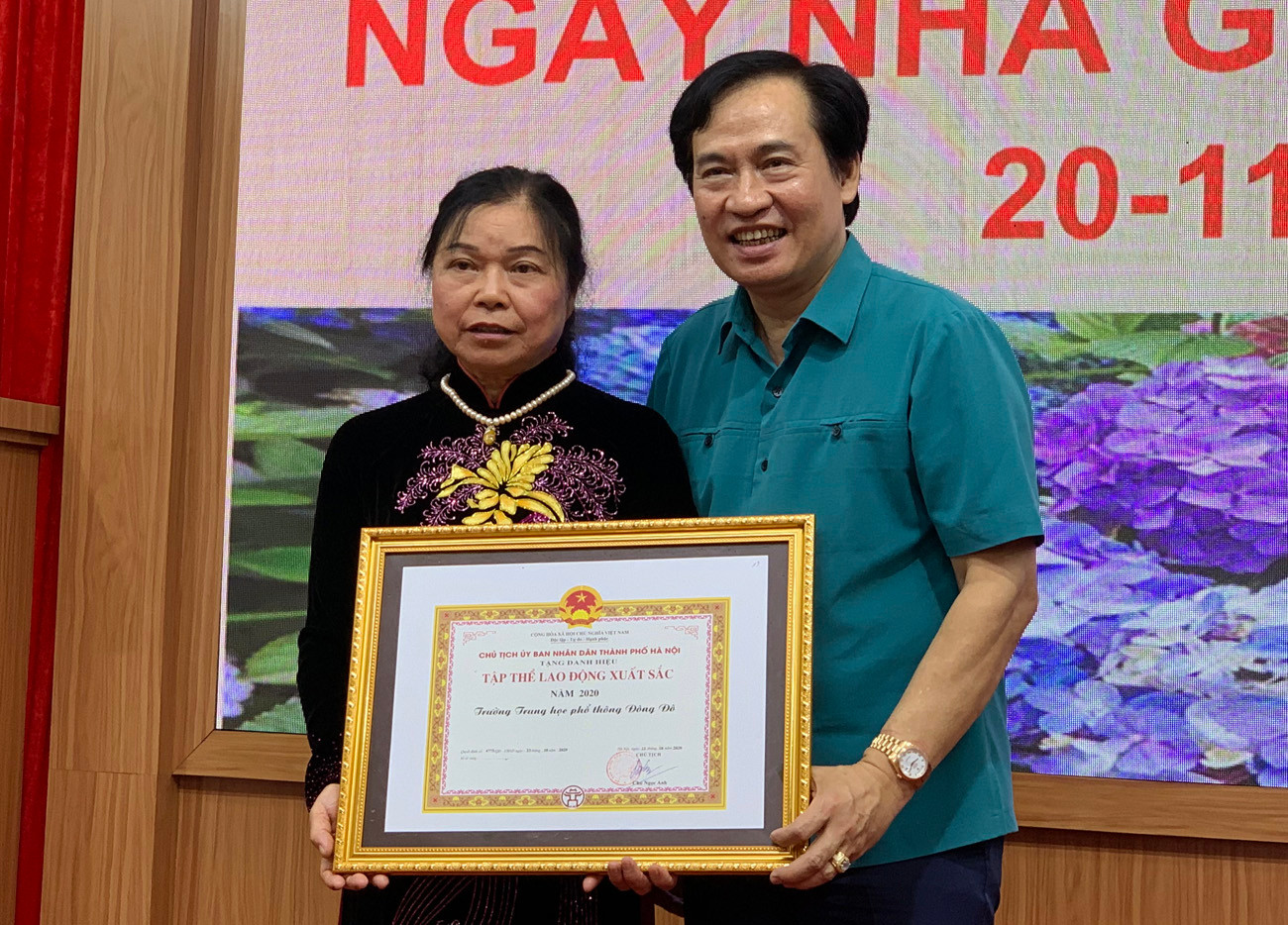 Ông Nguyễn Anh Tuấn (bên phải ảnh) Phó Bí thư thường trực quận Ủy Tây Hồ đang trao danh hiệu tập thể lao động xuất sắc cho cán bộ giáo viên Trường Trung học phổ thông Đông Đô. Ảnh: Tùng Dương.