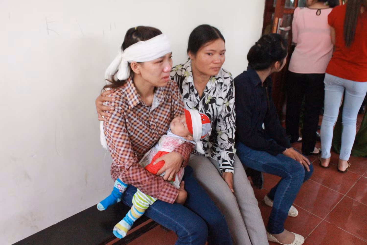 Vợ của nạn nhân Tuấn Anh, ôm con ngồi khóc bên ngoài phòng xử án.