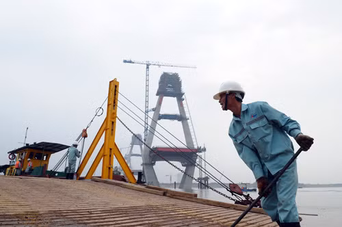 Đầu cầu hướng xã Vĩnh Ngọc, huyện Đông Anh, một số công nhân đẩy xà lan không hàng ra sông.