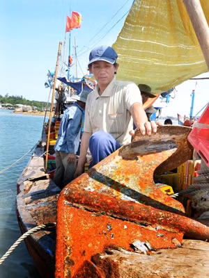Chủ tàu Trần Văn Quang và chiếc mỏ neo bị tàu Trung Quốc đâm lút vào mũi tàu. Ảnh: Đức Nguyễn. Chủ tàu Trần Văn Quang và chiếc mỏ neo bị tàu Trung Quốc đâm lút vào mũi tàu. Ảnh: Đức Nguyễn.