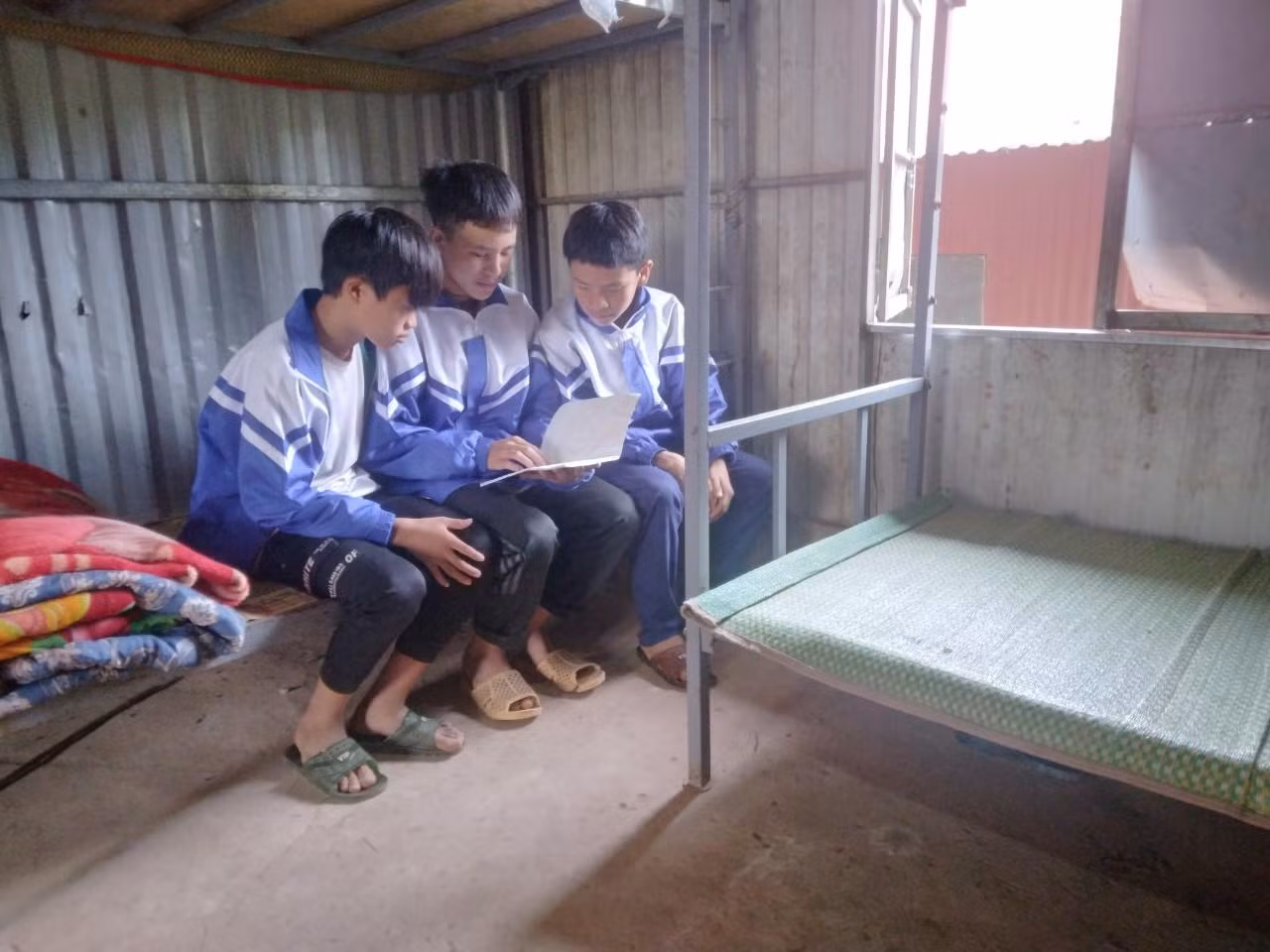 Các em học sinh vẫn cố gắng vượt qua khó khăn trong những phòng ngủ bằng tấm lợp để duy trì việc học tập. Ảnh: LC