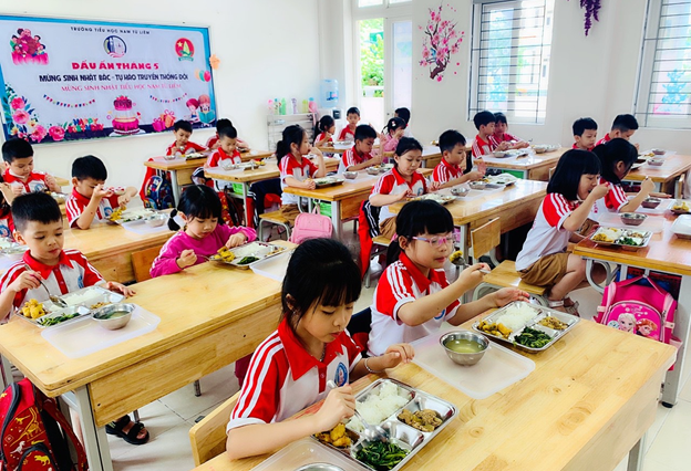 Các em học sinh trường tiểu học Nam Từ Liêm – Hà Nội thưởng thức thực đơn bữa trưa từ Phần mềm.