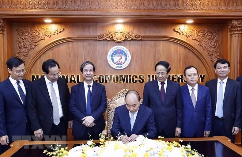 Chủ tịch nước Nguyễn Xuân Phúc viết lưu bút tại phòng truyền thống Trường đại học Kinh tế quốc dân. (Ảnh: Thống Nhất/TTXVN)