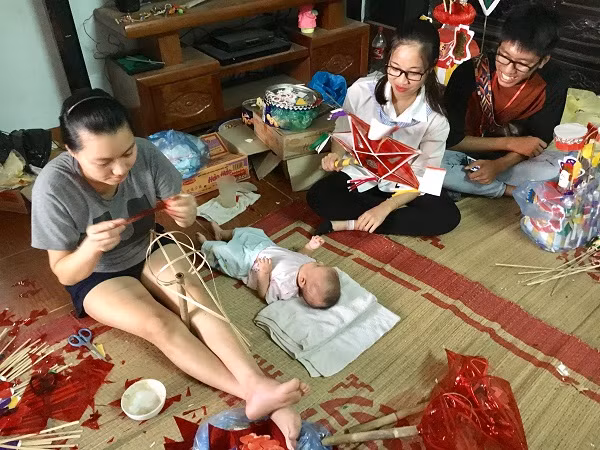 Chị Loan (trái), con gái thứ ba cùa bà Tuyến cho con gái 3 tháng tuổi đến nhà bố mẹ đẻ chơi và hỗ trợ ông bà làm đồ Trung thu. (Ảnh: Hồ Thu)