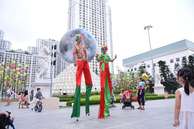 Quảng trường Vincom Mega Mall Royal City trở thành một sân chơi sôi động đậm chất lễ hội. Từ 17 giờ chiều, trong lúc chờ thắp sáng “siêu trăng”, rất đông người đã tề tựu tham gia hoạt động thú vị như treo điều ước lên hàng tre ước nguyện, chụp ảnh lấy ngay miễn phí, xem biểu diễn đi cà kheo...