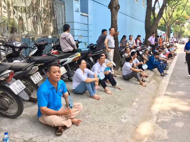 Nhiều phụ huynh chọn ngồi dưới bóng cây để chờ con cho đỡ nắng.