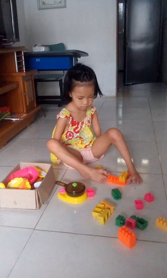 Linh khéo léo xếp đồ chơi bằng đôi chân. Linh khéo léo xếp đồ chơi bằng đôi chân.