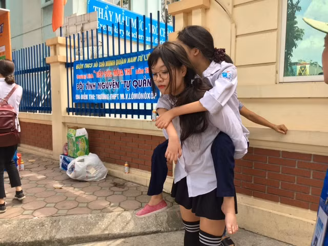 Hình ảnh nữ sinh cõng bạn tật nguyền ở điểm thi làm nhiều người chú ý.