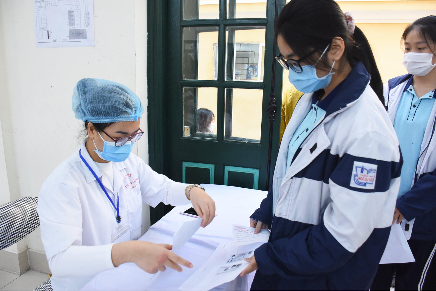 Nhân viên y tế kiểm tra danh sách học sinh đăng ký tiêm (Ảnh: NH)