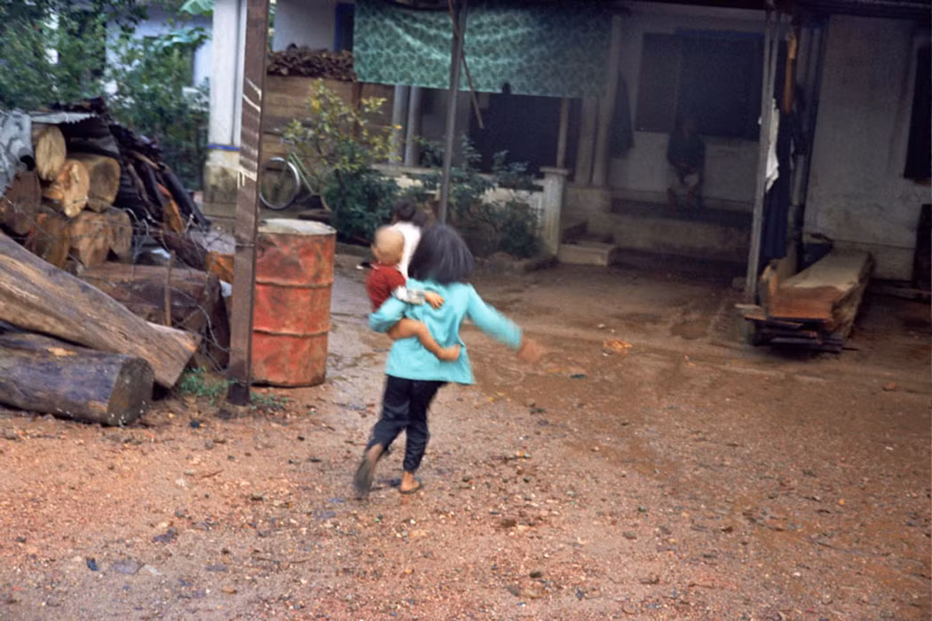 Một bé gái người nhà cô dâu đang ẵm đứa em trai.