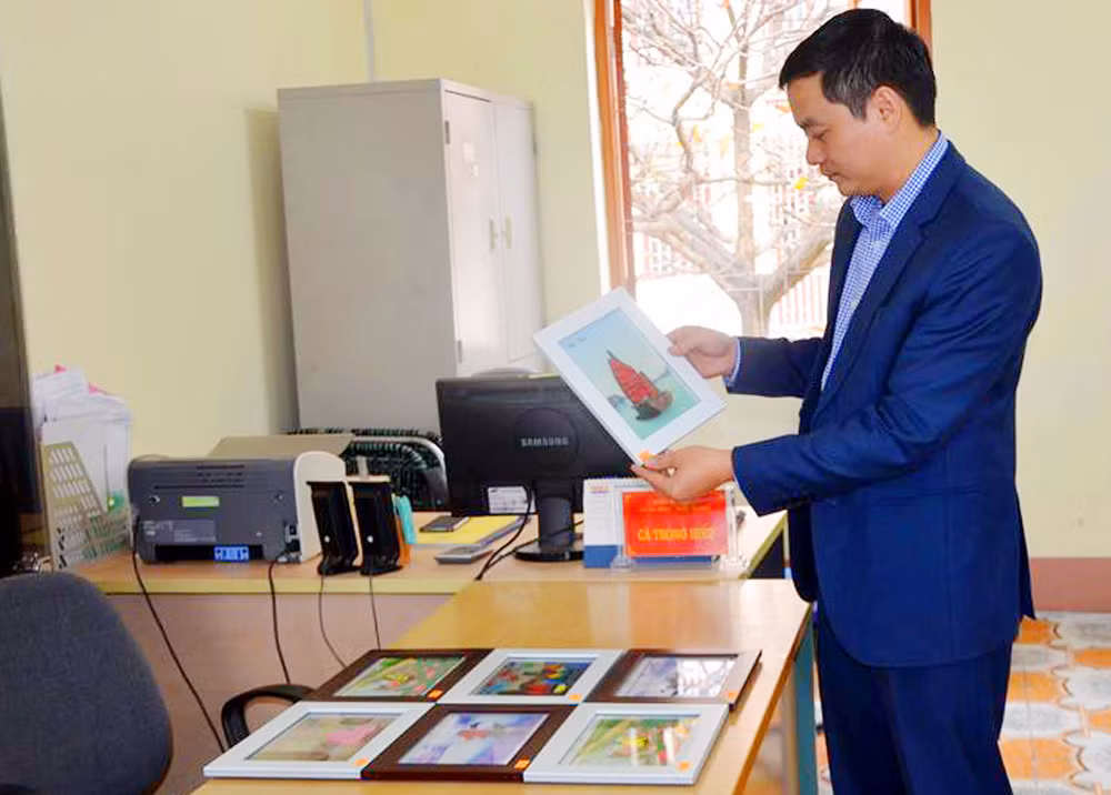 Thầy giáo Hiếu giới thiệu những sản phẩm tranh giấy do các học sinh khiếm thính làm. (Ảnh: Cộng tác viên)